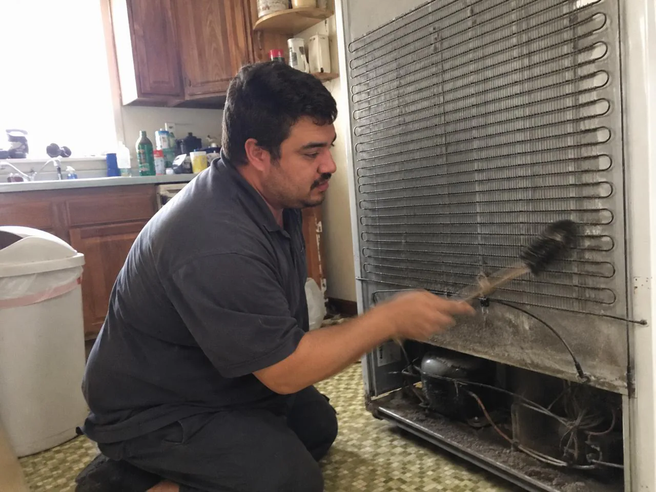 Technician repairing a refrigerator in a home kitchen